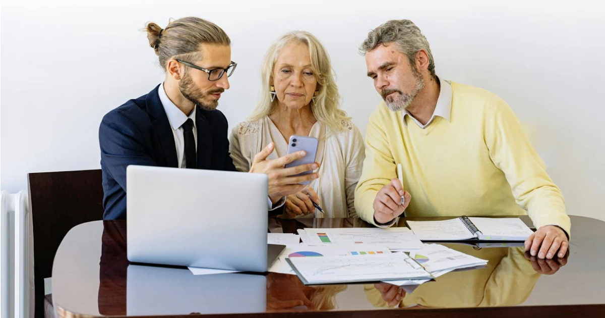 A photo of an insurance broker having a conversation with two seniors about general insurance QLD.